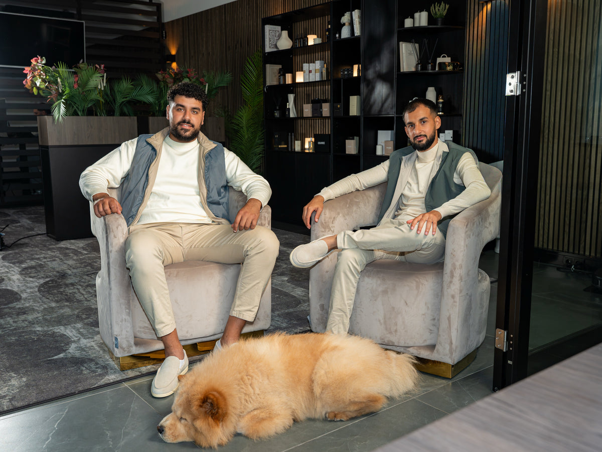 Marco en Kiro, de oprichters van Oduree, in fauteuils in de lounge, met de hond aan hun voeten.